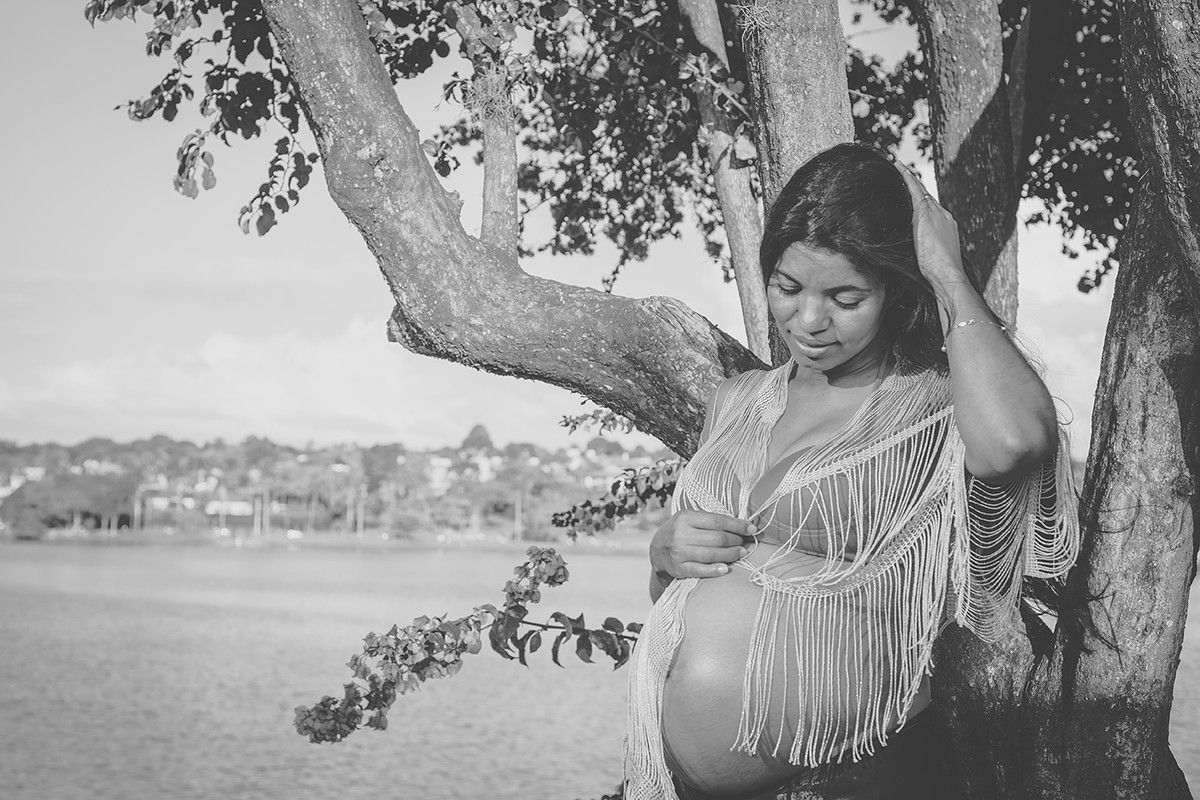 Gestante olhando para a barriga próximo a uma árvore na bela paisagem da lagoa da Pampulha em Belo Horizonte BH MG