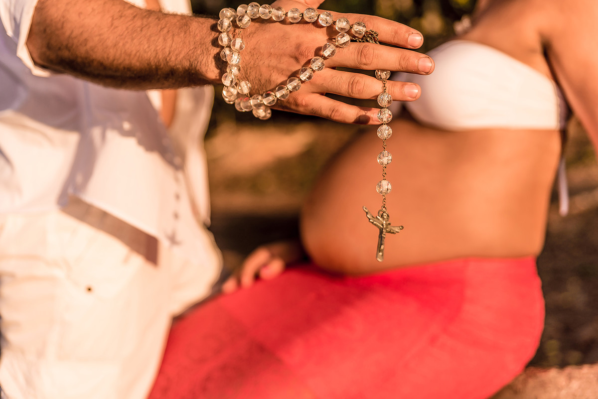 Gestante com terço na mão no ensaio de gestante na ilha do Boi ES