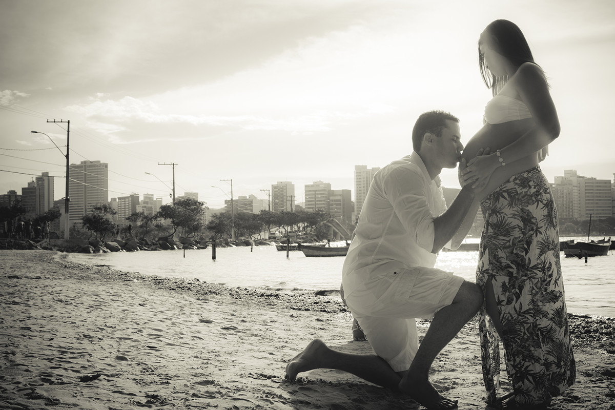 pai beijando a barriga da gestante no ensaio de gestante na praia na ilha do Boi ES