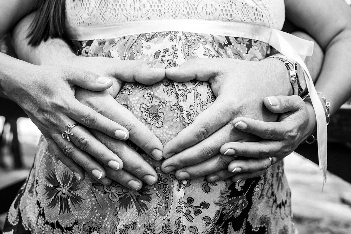 Mãos segurando a barriga da gestante no ensaio de gestante em Vitória ES