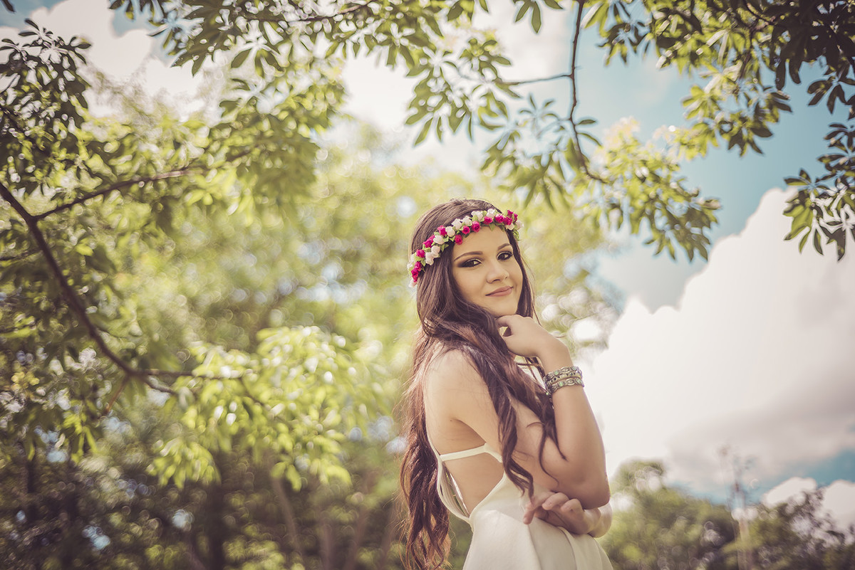 Debutante com a mão no queixo entre as arvores no parque das águas no barreiro em Belo Horizonte BH MG