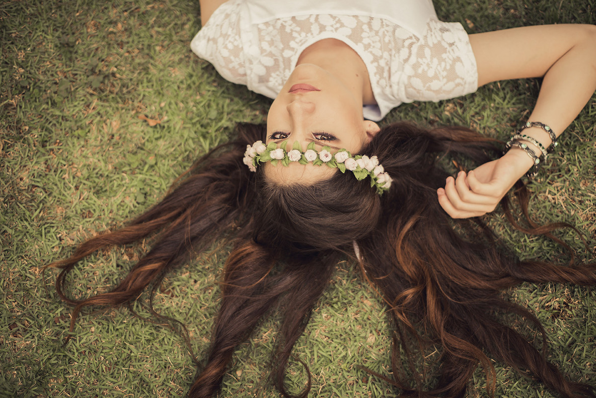 Debutante feliz deitada na grama do parque das águas no ensaio de debutante feito pelo fotógrafo de 15 anos em Belo Horizonte BH MG