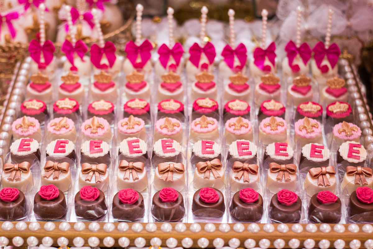 doces enfeitando a mesa principal, coroas e laços dão um charme a esses deliciosos docinhos