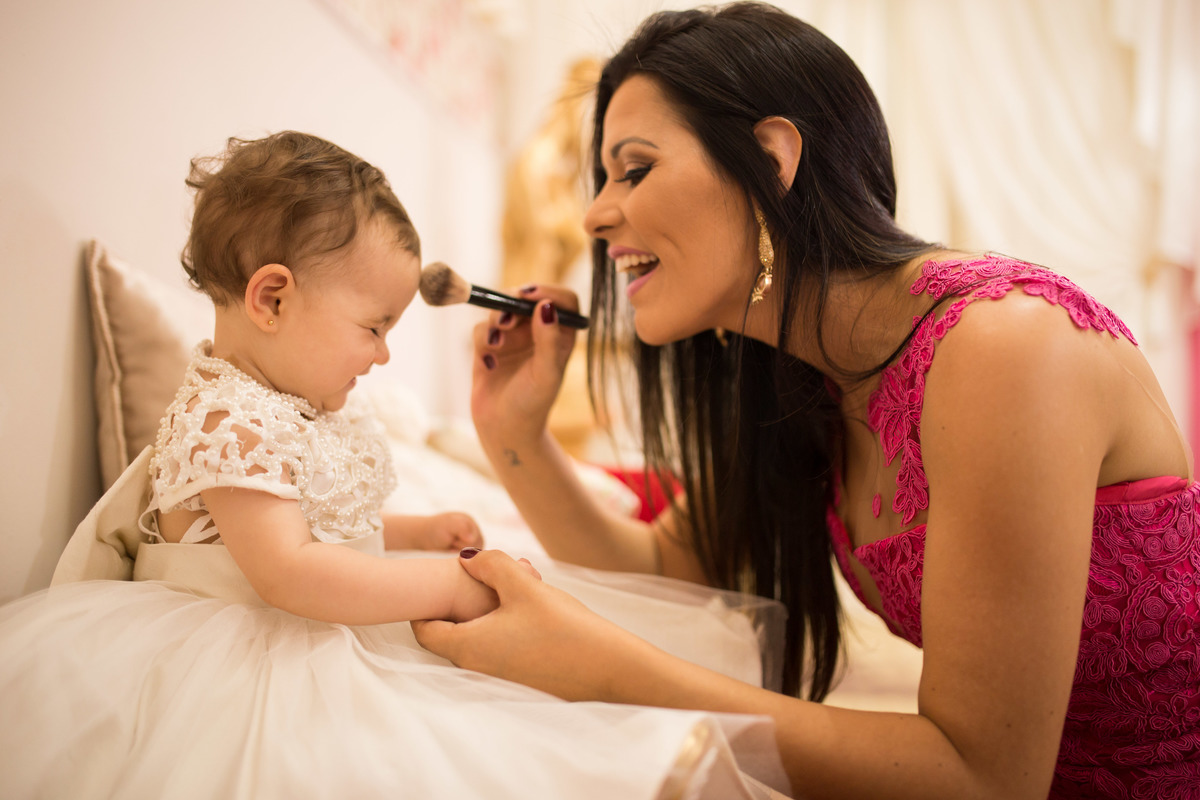 mamãe fazendo carinho com pincel de maquiagem na bebê