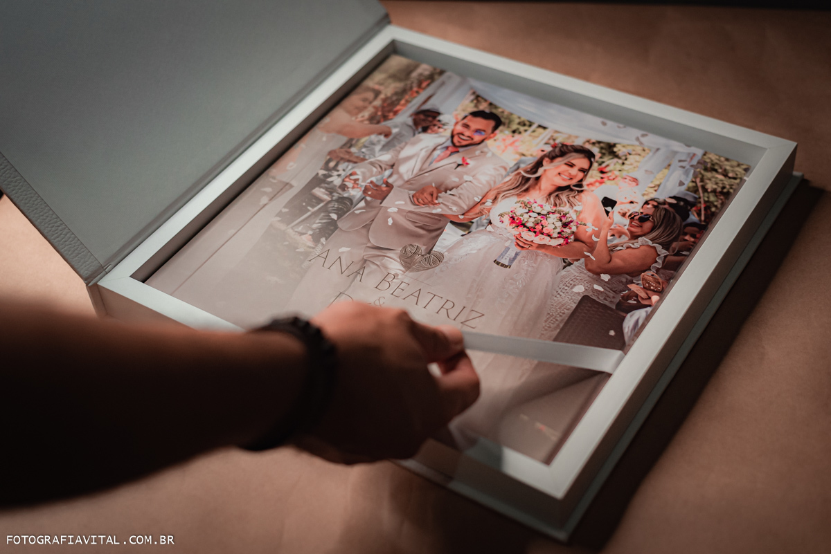 casamento_microwedding_shuibrasil_pureza_riograndedonorte_campo_arlivre_álbum_de_casamento_ foto da box do álbum aberta. Dentro vemos o álbum  e uma mão puxa a fita para retirá-lo.
