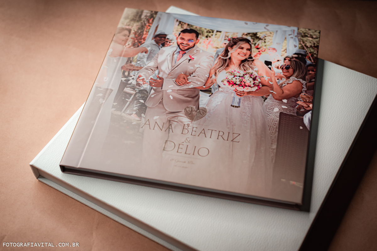 casamento_microwedding_shuibrasil_pureza_riograndedonorte_campo_arlivre_álbum_de_casamento _Álbum fora da box. Na capa vemos uma foto do casal na saída do casamento. Eles sorriem entre as pétalas de rosas jogadas pelos convidados.