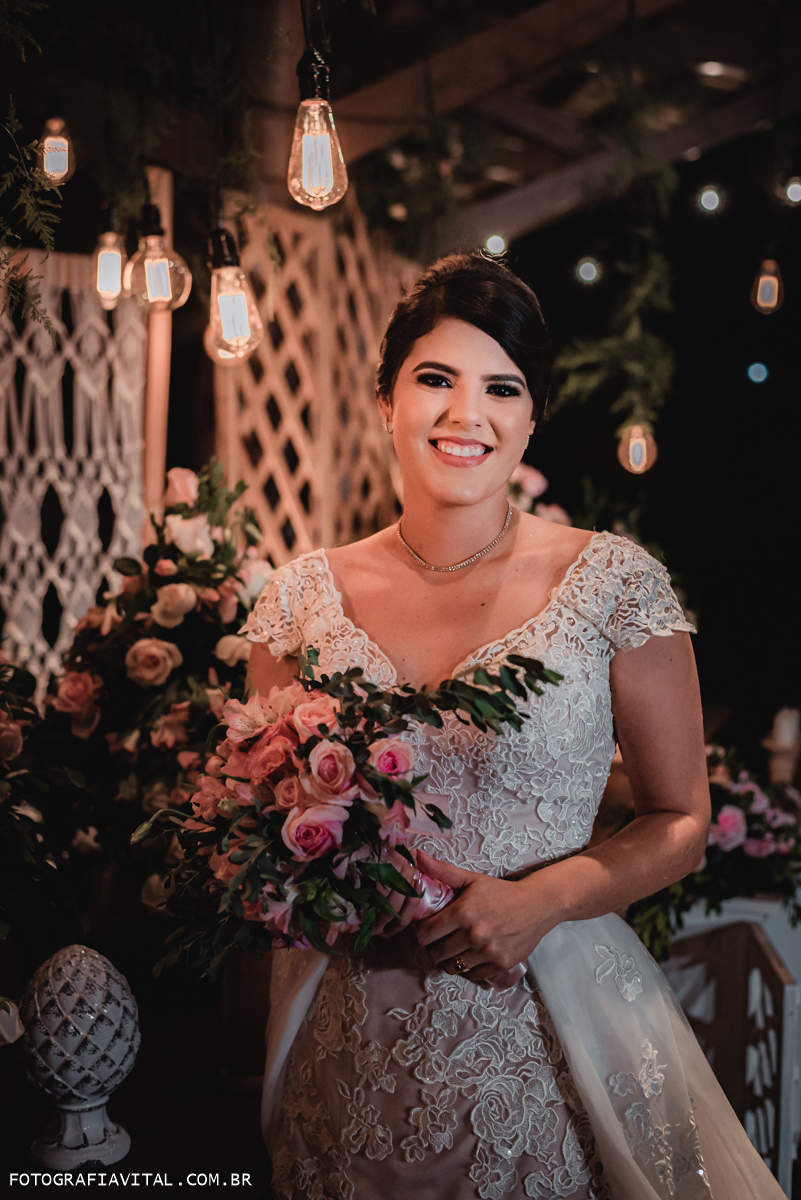 Fazenda Real III - Macaíba - RN - Retrato da noiva segurando o buque e sorrindo, olhando para a lene. Ela está de costas para a mesa do bolo.