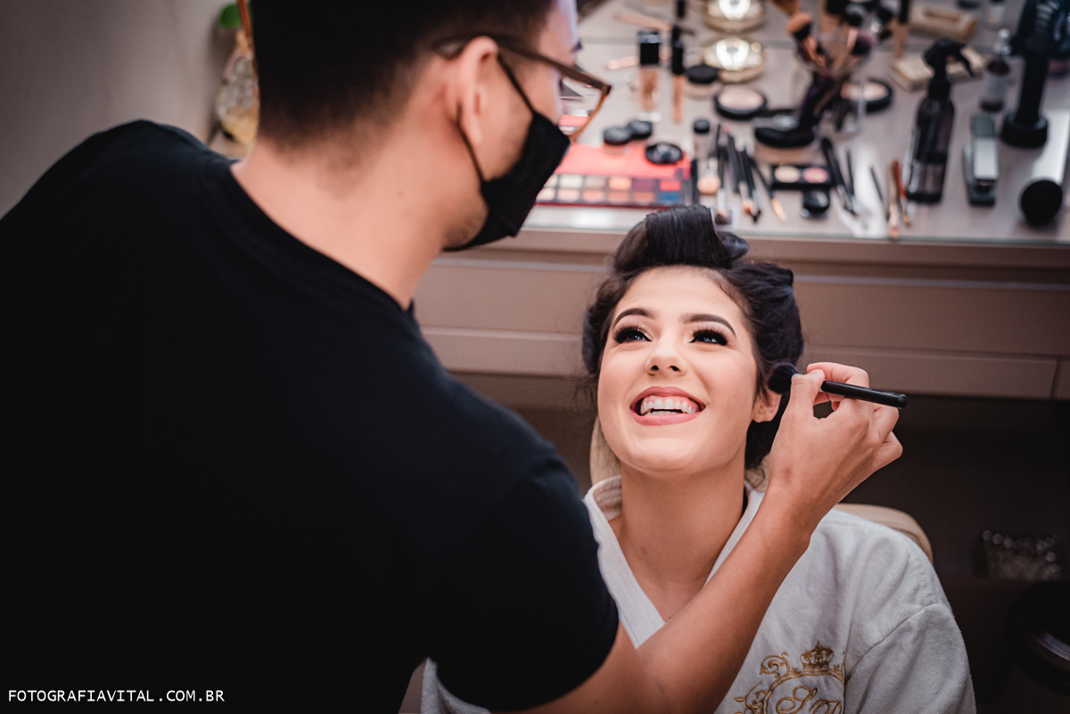 Estúdio Pontes - Natal - RN - Noiva olhando apra o maquiador e sorrindo. enquanto isso ele segura o pincel próximo ao seu rosto.