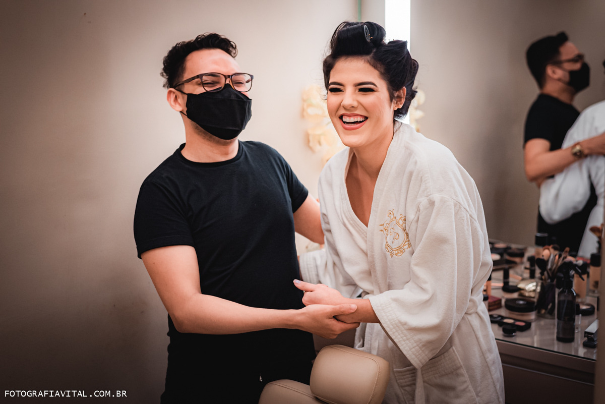 Estúdio Pontes - Natal - RN - A noiva e o maquiador estão de mão dadas sorrindo.