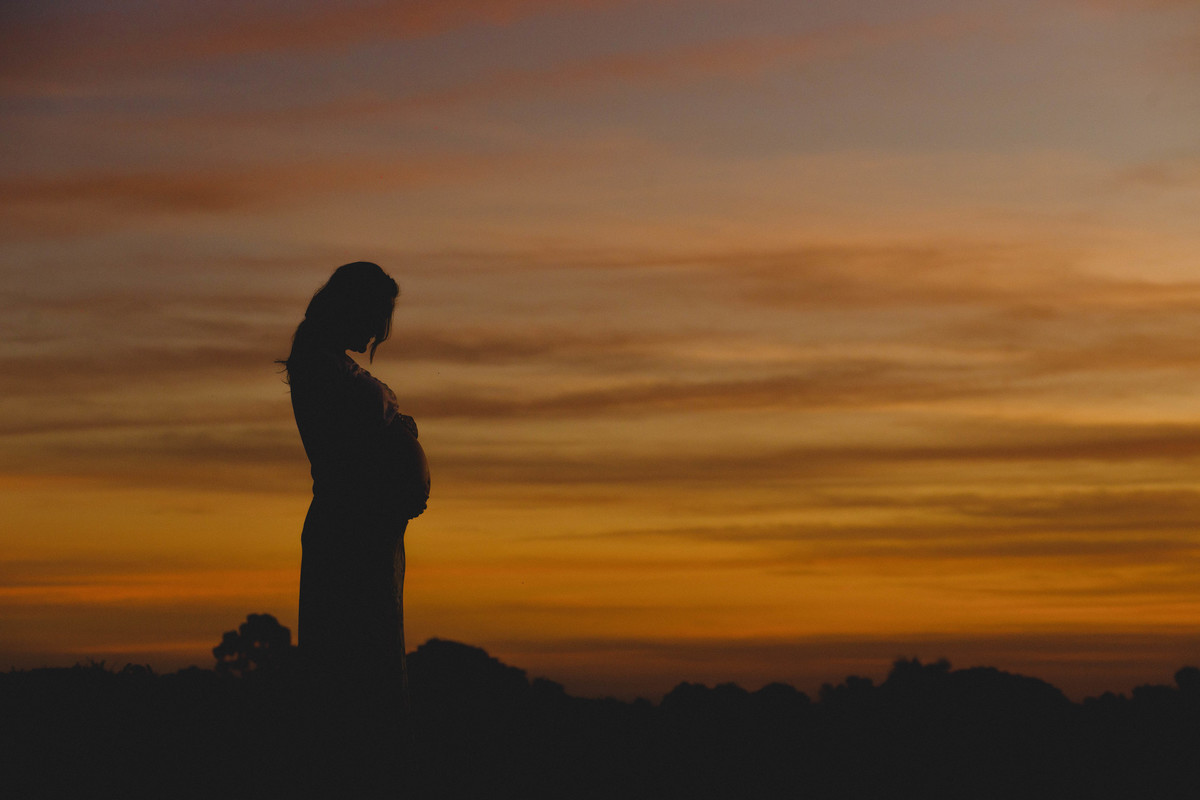mamãe tocando a barriga no por do sol