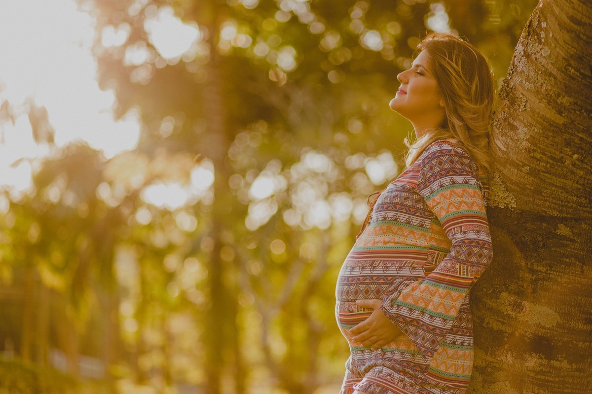 gestante encostada na arvore pensando no bebe que esta em seu ventre