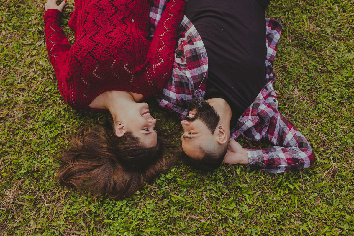 casal se olhando deitado na grama de cabeça para baixo