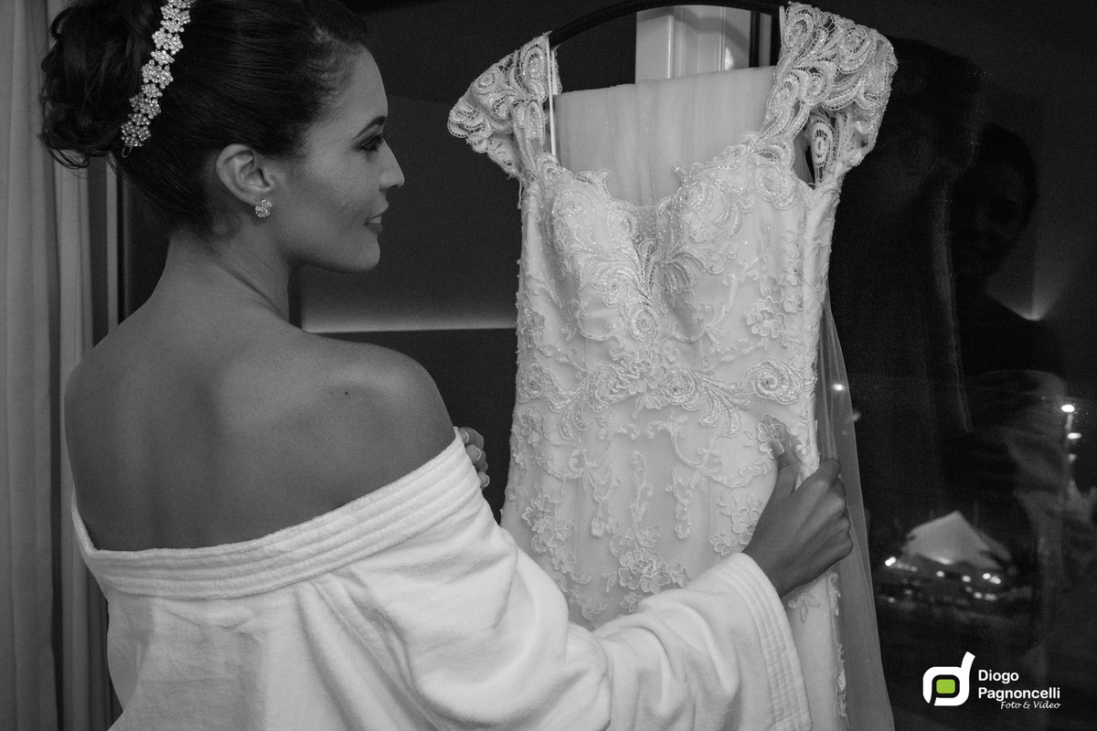 Noiva em preto e branco olhando o vestido com janela de fundo. Foto Diogo Pagnoncelli.