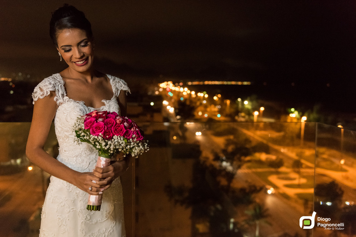 Vista noturna da praia do recreio com noiva olhando o bouquet de rosas. Foto Diogo Pagnoncelli.