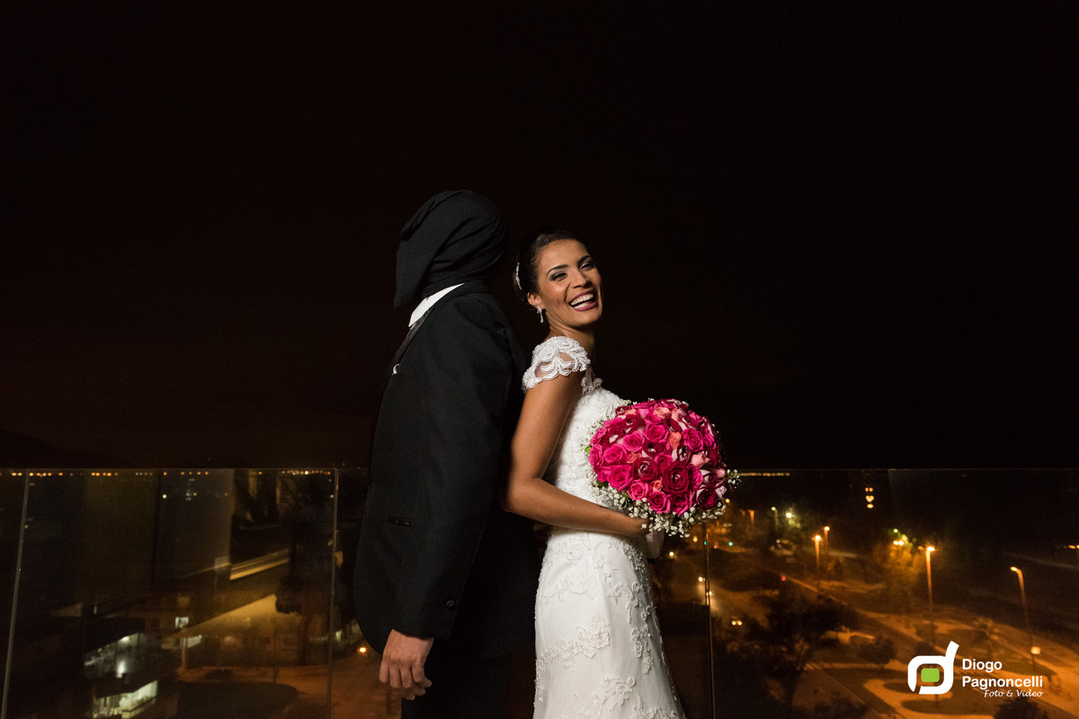 First look com noivo com capuz e noiva de costas para o noivo com bouquet de rosas nas mãos. Foto Diogo Pagnoncelli.