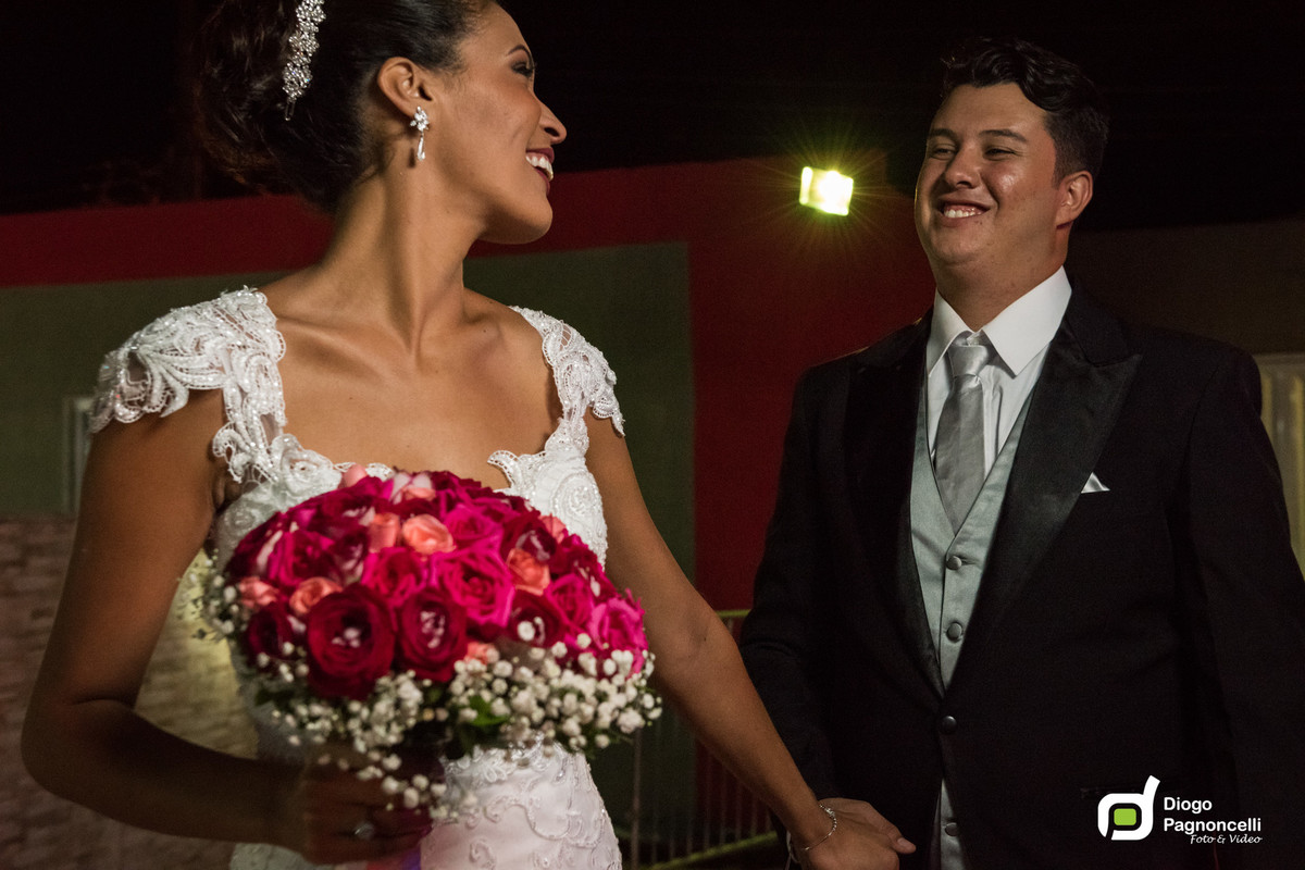 Noiva andando com o bouquet e olhando para o noivo. Foto Diogo Pagnoncelli.