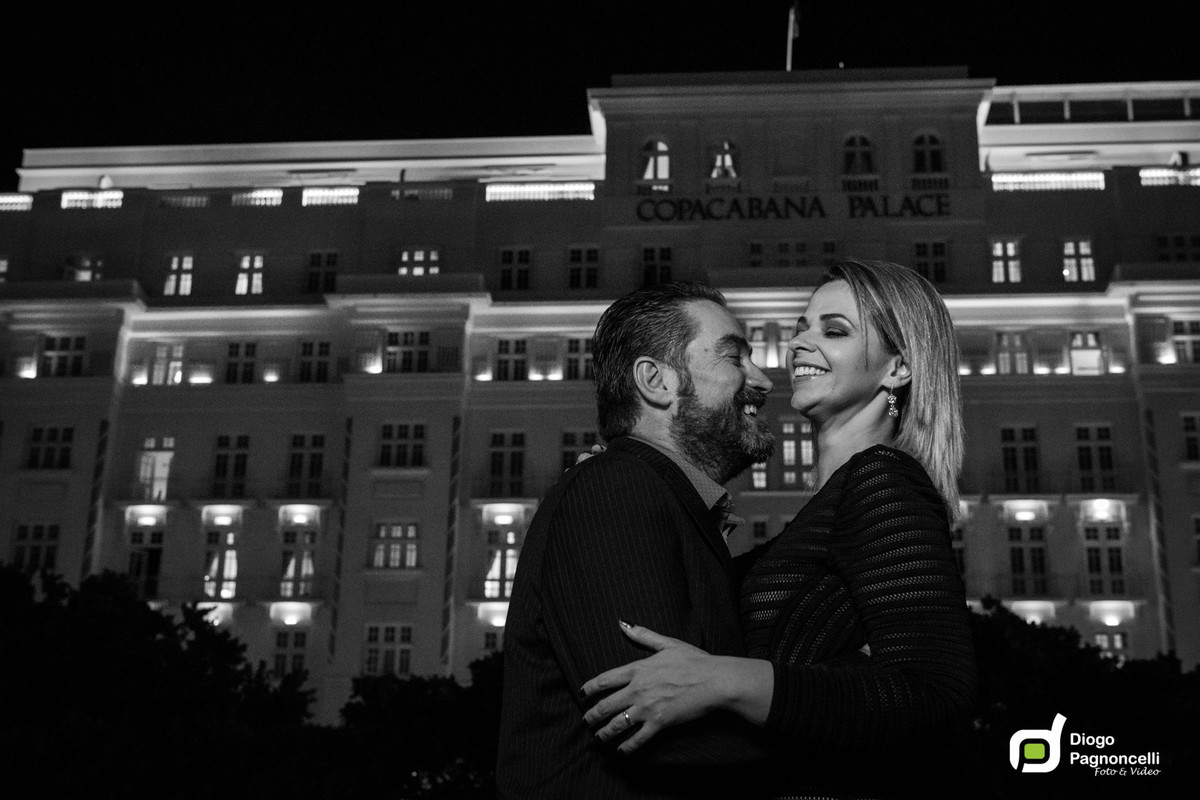 Casal apaixonado se olhando com o Copacabana Palace de fundo em preto e branco. Foto Diogo Pagnoncelli.