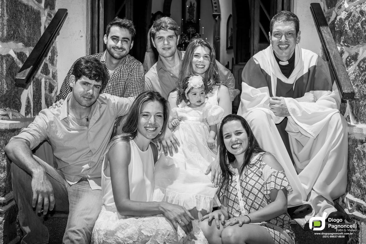 Padre, padrinhos e pais posando com a criança batizada na porta da igreja. Foto Diogo Pagnoncelli.