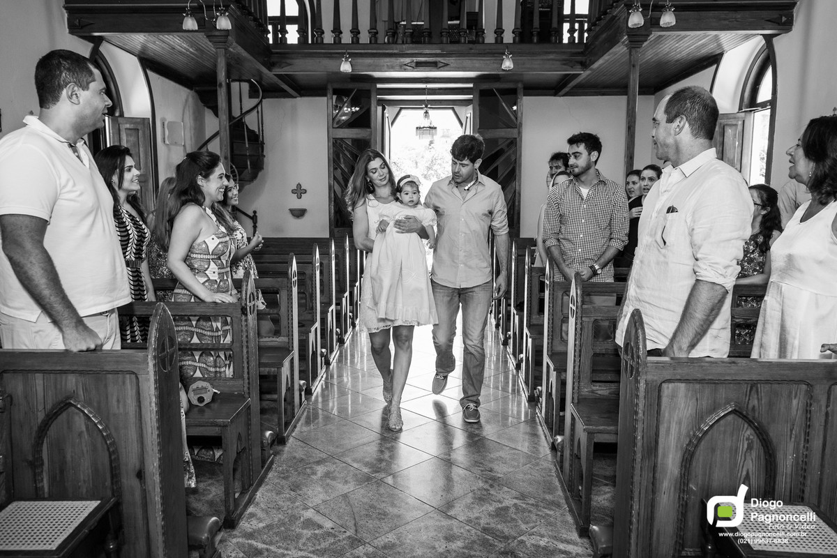 Pais entrando pelo corredor da igreja com a filha que será batizada no colo. Foto Diogo Pagnoncelli.