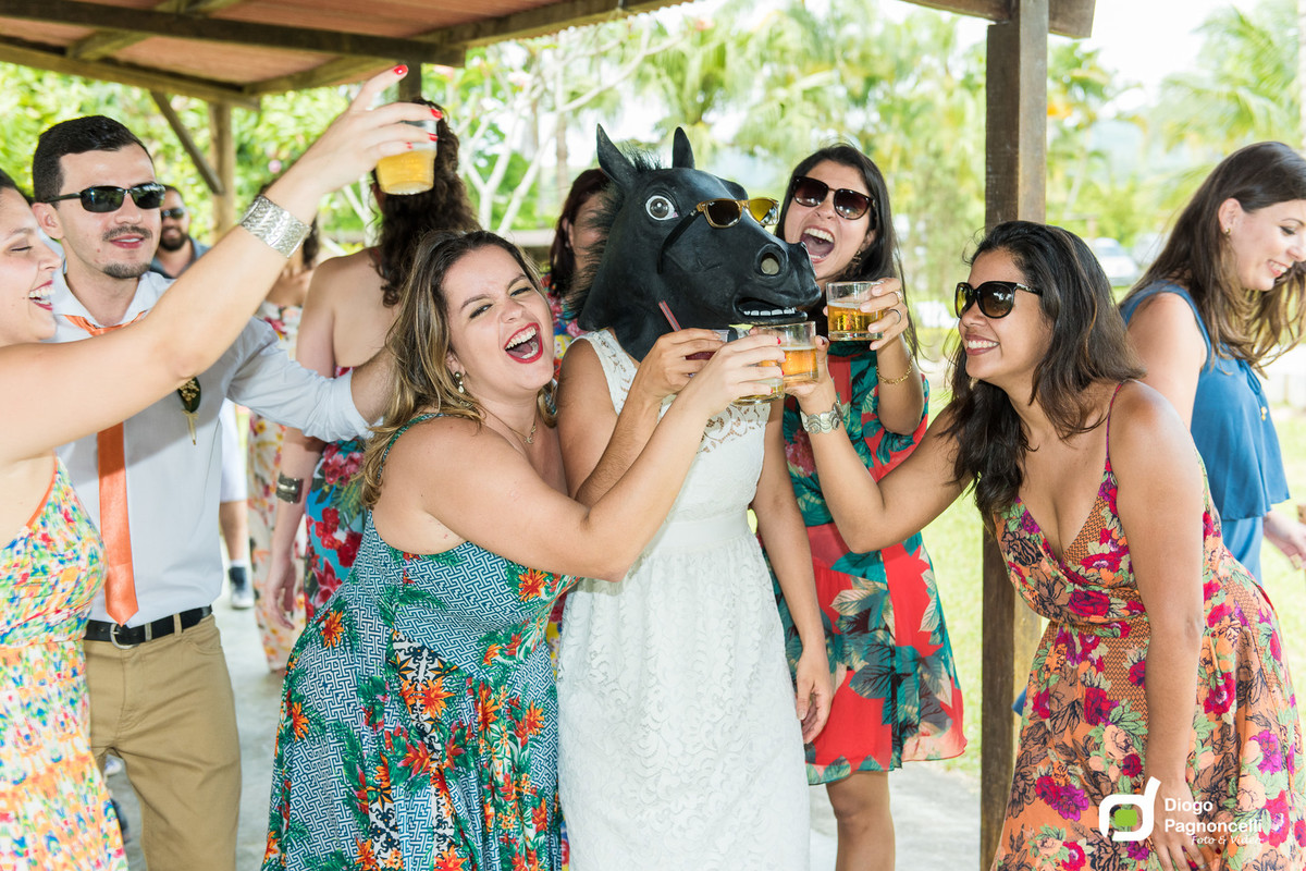 Noiva com mascara de cavalo brindando e curtindo a festa do casamento com as amigas. Foto Diogo Pagnoncelli.