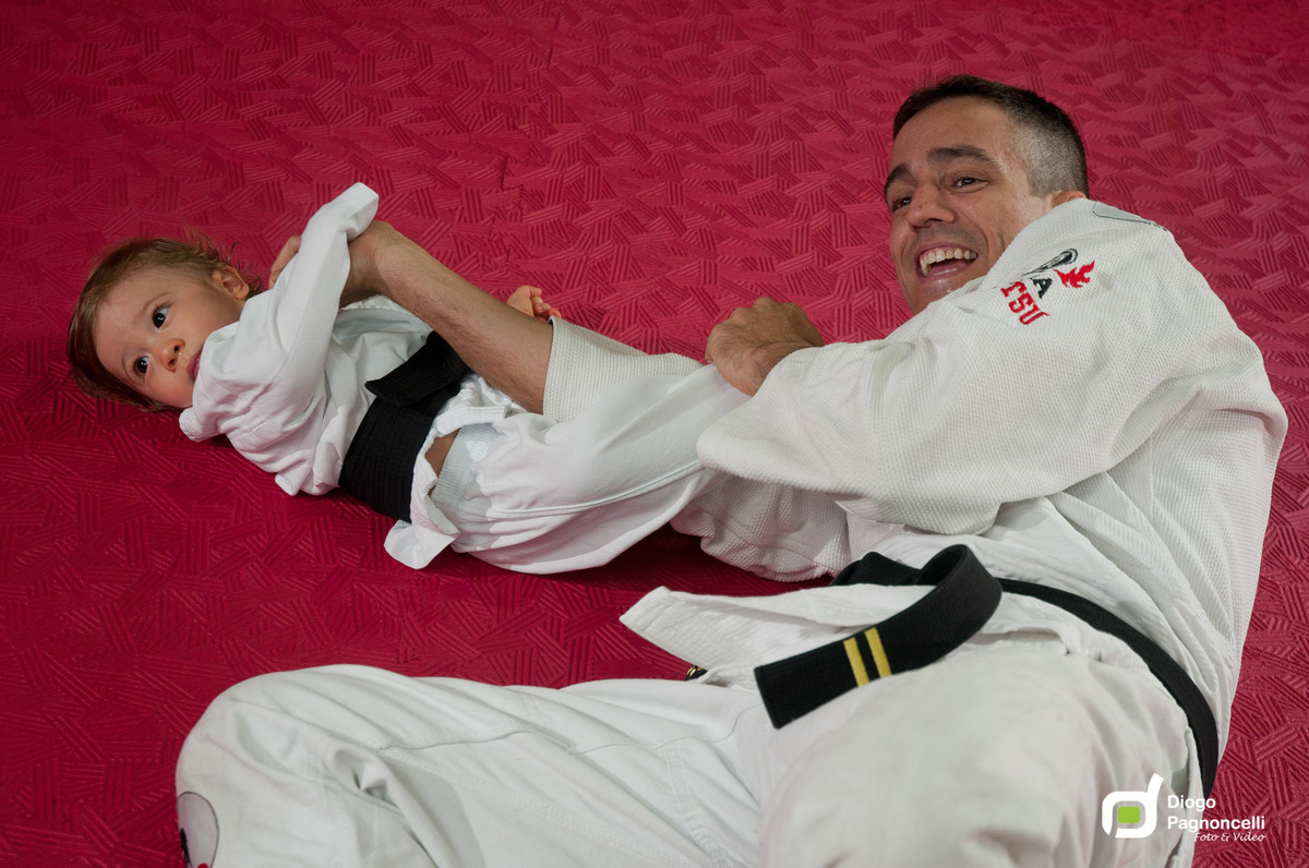 Pai e filho de quimono brincando de Jiu-jitsu na academia de ginastica da família. Foto Diogo Pagnoncelli