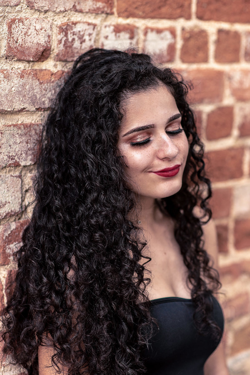 encostada em uma parede de tijolinhos olhando pra baixo