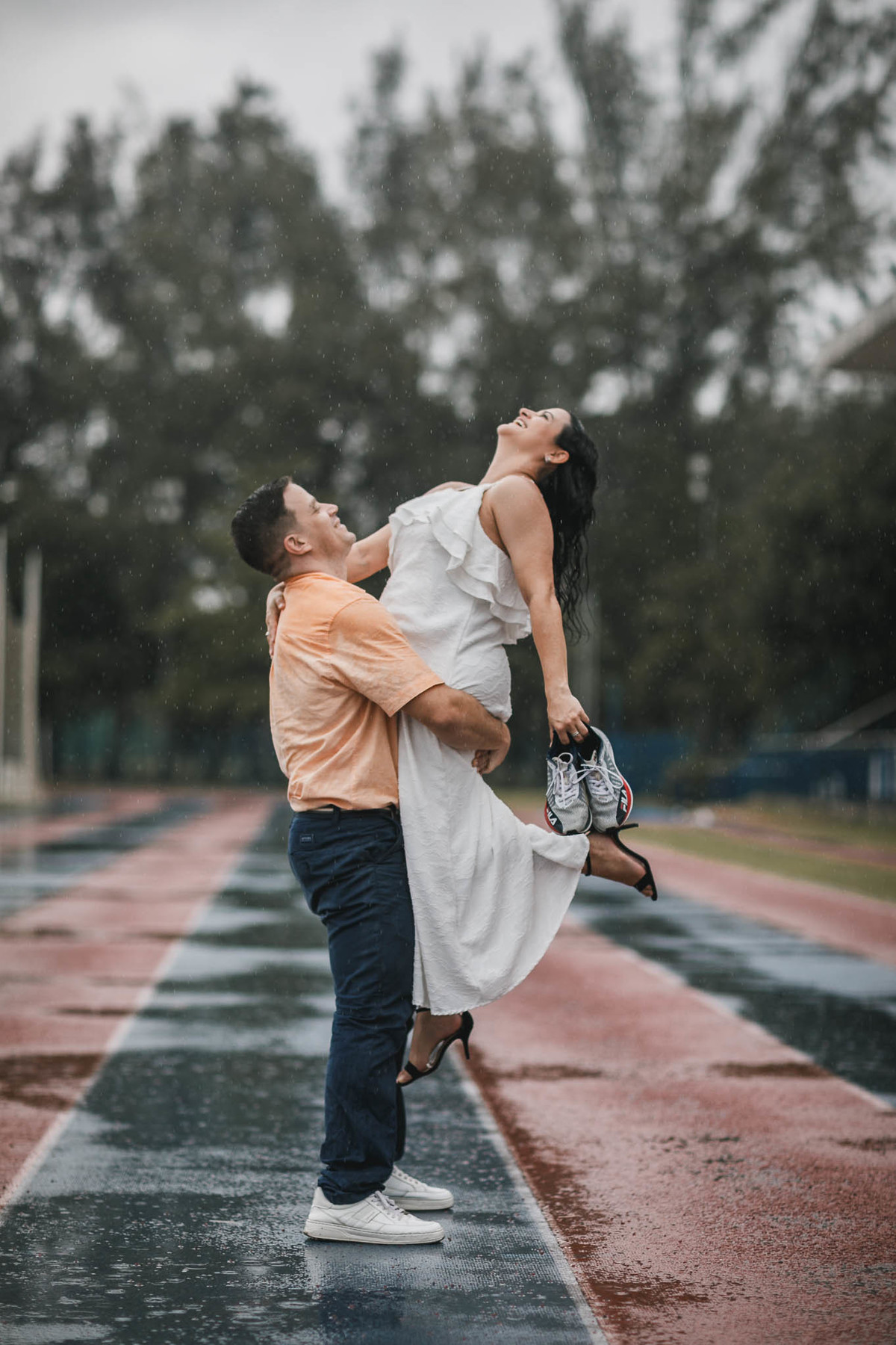 Fotos de pre-wedding na chuva na pista de atletismo.