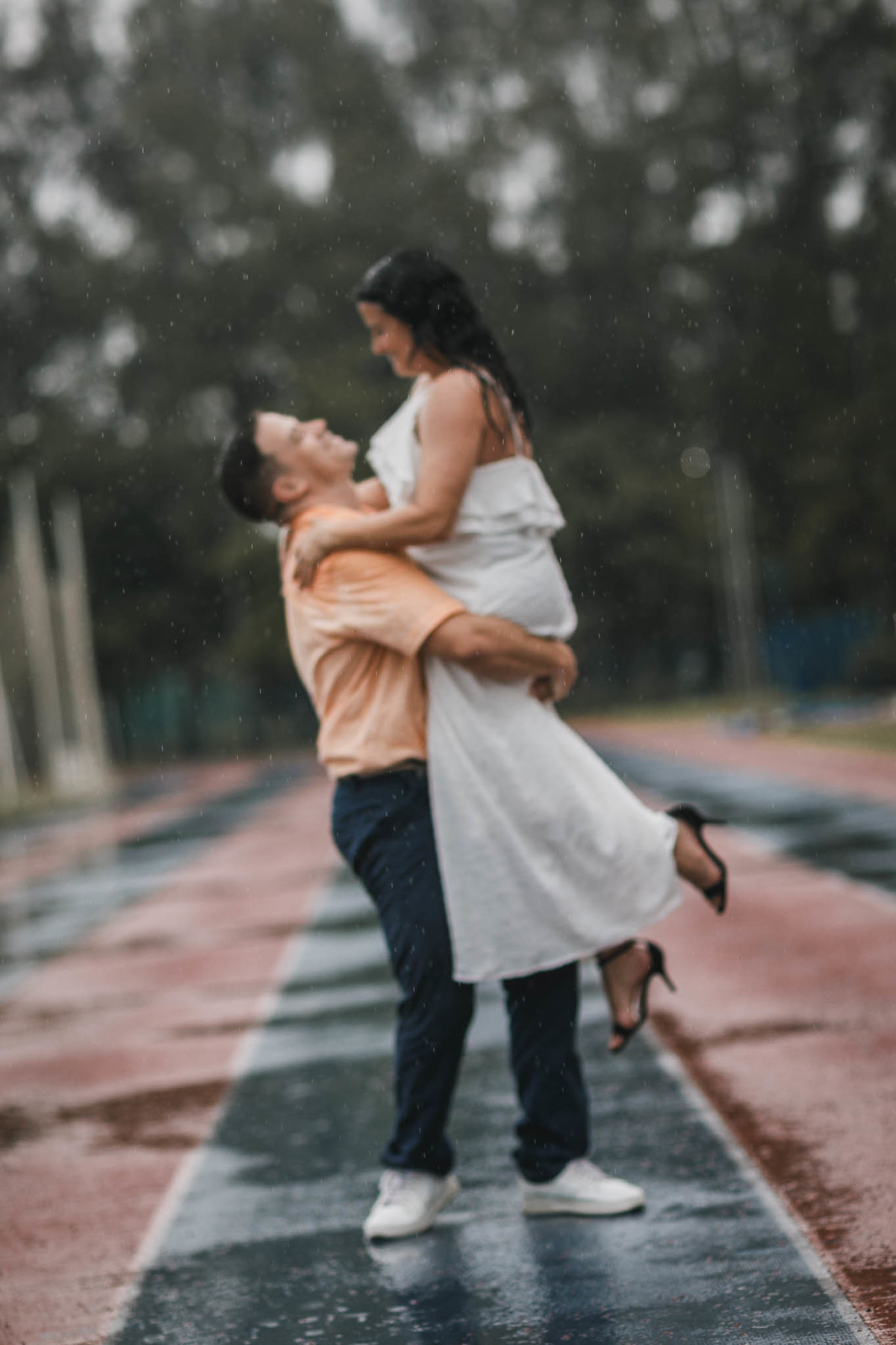 Fotos de pre-wedding na chuva na pista de atletismo.