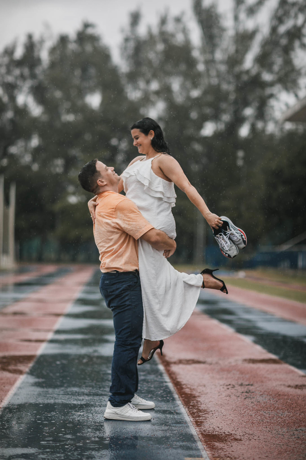 Fotos de pre-wedding na chuva na pista de atletismo.