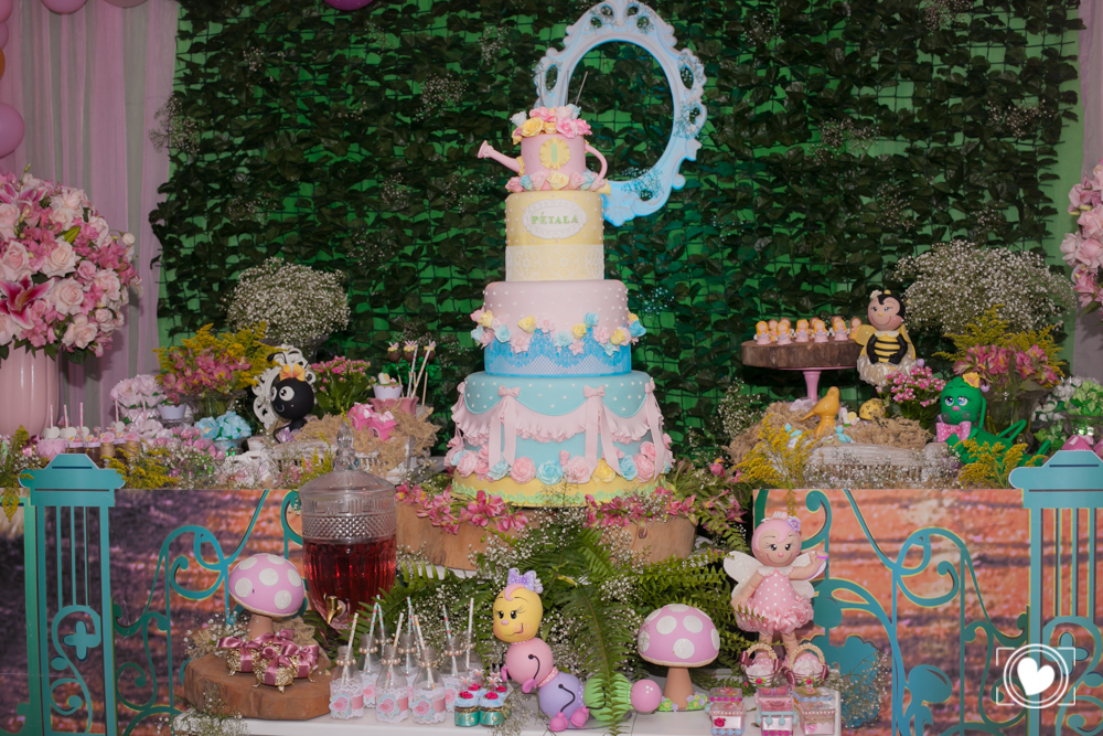 centro da mesa dando destaque ao grandioso bolo de quatro andares desta festa infantil.