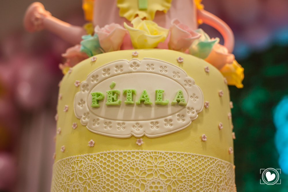 segundo andar do grande bolo, todo em amarelo, com flores rosa claro e coberto por renda branco que deu o charme a decoração.