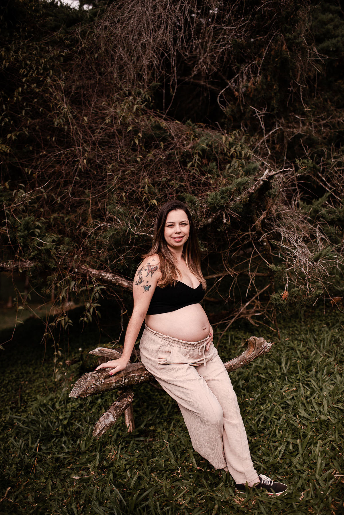 ensaio externo de gestante em nova friburgo, região serrana do rio de janeiro. Foto da gestante sentada no tronco de uma árvore no chão