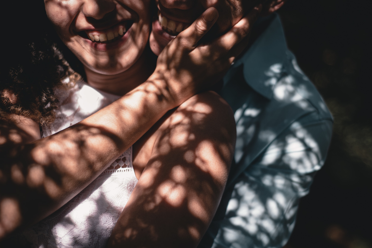 Ensaio Pré Casamento em Nova Friburgo, foto conceitual mostrando da altura do nariz para baixo do casal sorrindo e os galhos em volta fazendo sombra em seus rostos