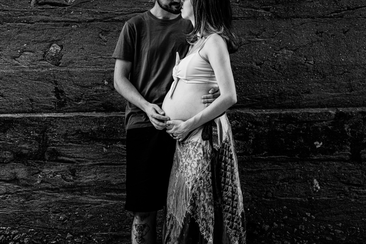 Ensaio externo de gestante em Nova Friburgo, foto em preto e branco do companheiro dando um beijo na gestante