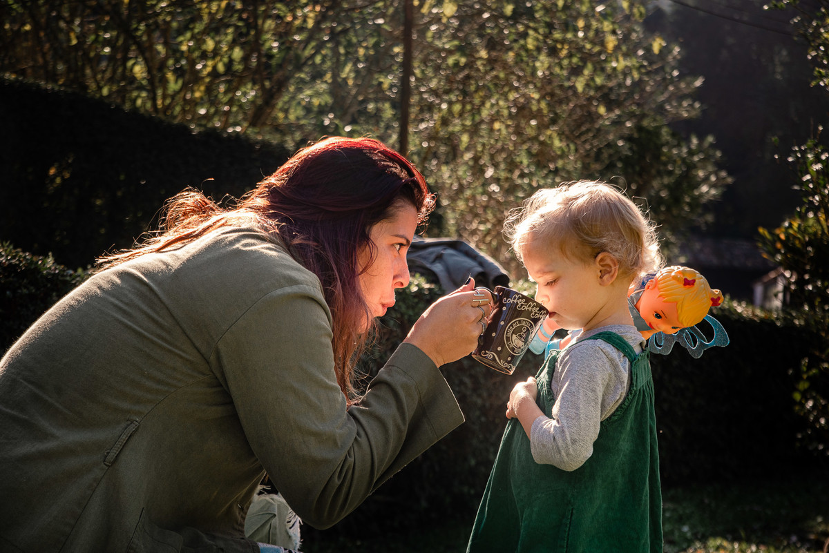 Fotógrafo de família em Nova Friburgo. Ensaio documental de família. Foto da tia dando leite para a criança na caneca