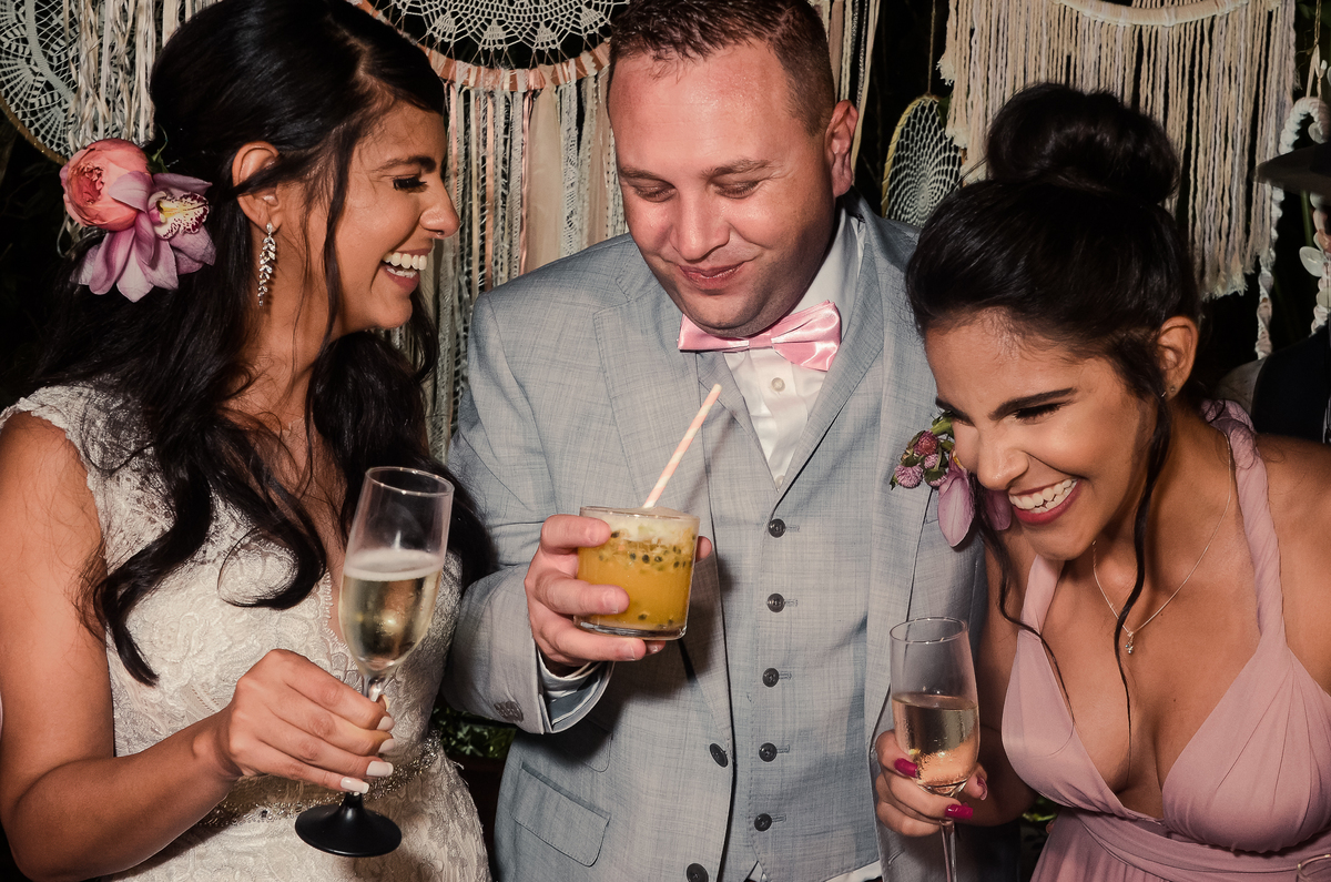 Fotografo de Casamento em Nova Friburgo - RJ. Destination Wedding em Paraty Mirim. Foto dos noivos com a madrinha rindo com copos de drink na mão