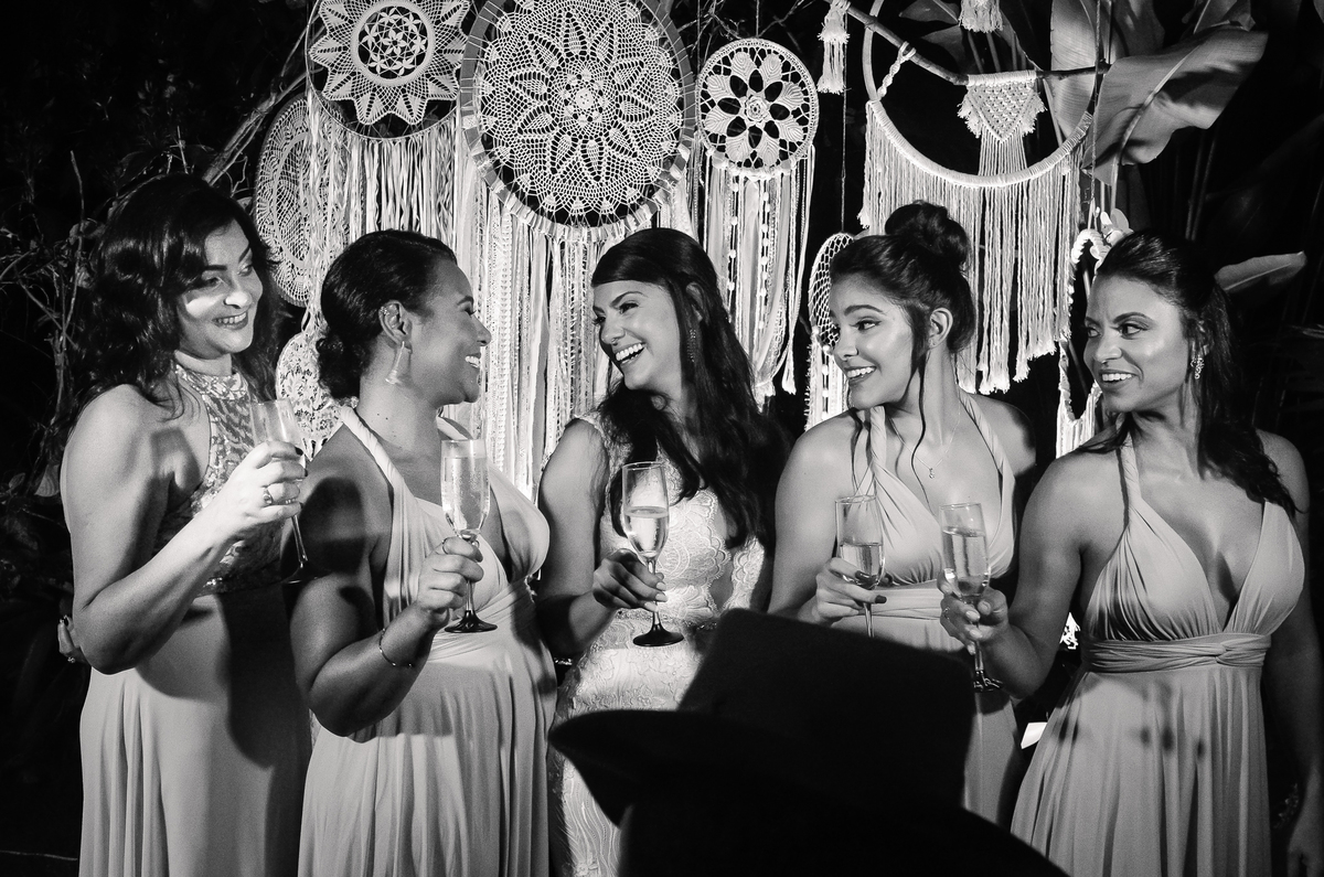 Fotografo de Casamento em Nova Friburgo - RJ. Destination Wedding em Paraty Mirim. Foto em preto e branco das madrinhas fazendo um brinde com a noiva na recepção do casamento