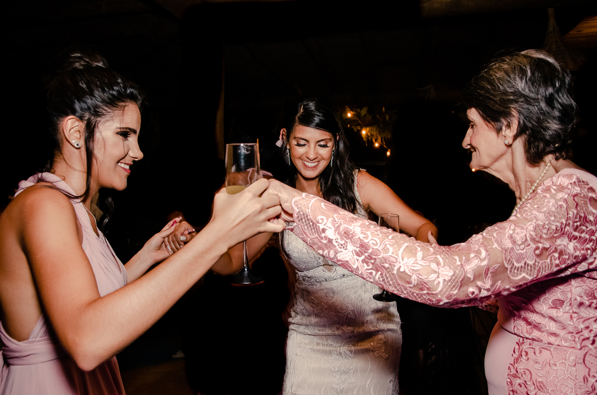 Fotografo de Casamento em Nova Friburgo - RJ. Destination Wedding em Paraty Mirim. Foto da noiva e madrinha dançando de mãos dadas com a avó durante a festa de casamento