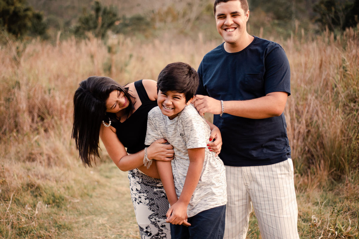 Ensaio externo de gestante em Nova Friburgo, foto de família com a gestante e o companheiro brincando com o filho mais velho
