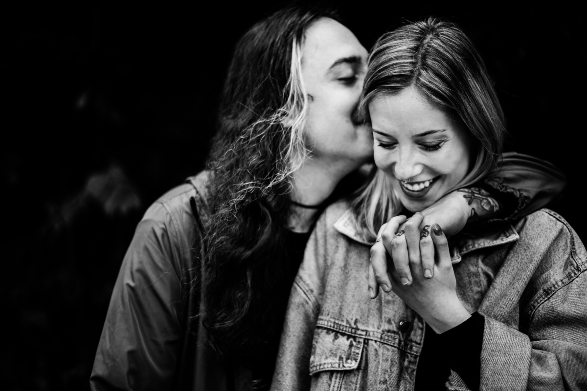 Fotógrafo de casamento em Nova Friburgo. Ensaio pré wedding do casal. Foto em preto e branco do casal abraçado e o namorado dando um beijo na namorada que está sorrindo