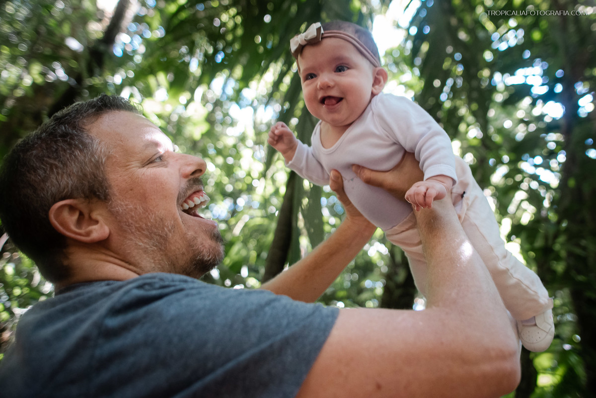 Ensaio documental de família em casa feito por fotógrafos em nova friburgo região serrana do rio de janeiro. Foto do pai levantando a filha nos braços