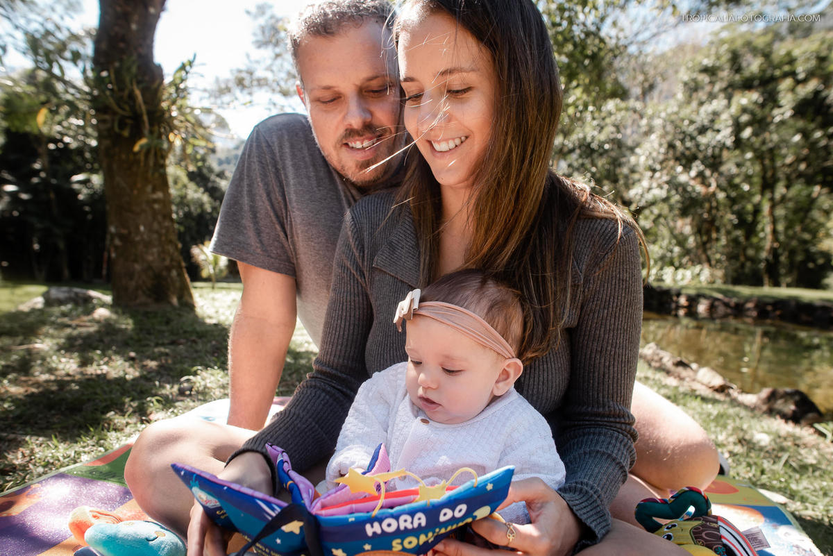 Ensaio documental de família em casa feito por fotógrafos em nova friburgo região serrana do rio de janeiro. Foto dos pais com a filha brincando no chão