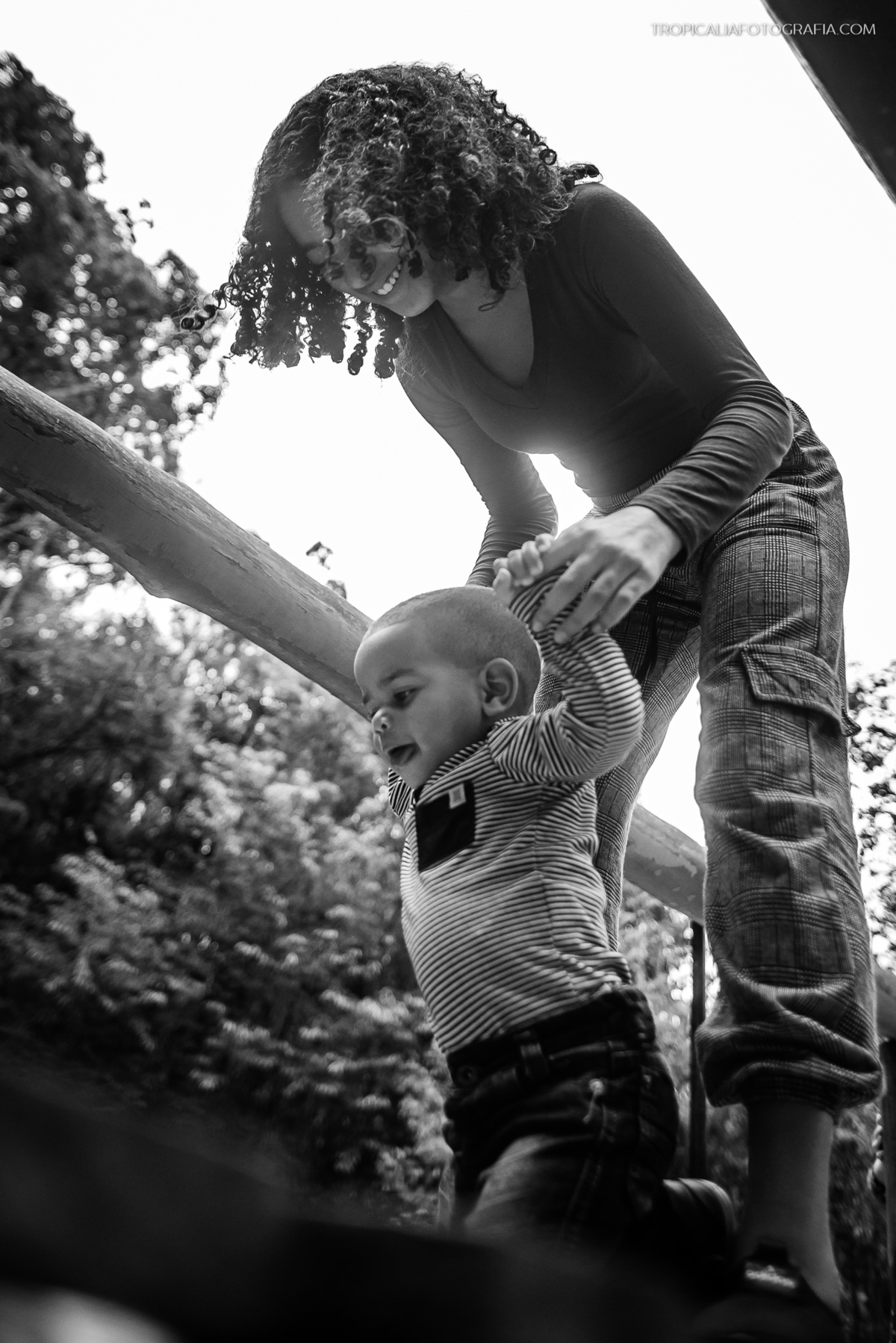 Ensaio documental de família em Nova Friburgo. Foto em preto e branco da criança brincando com a irmã mais velha no parque