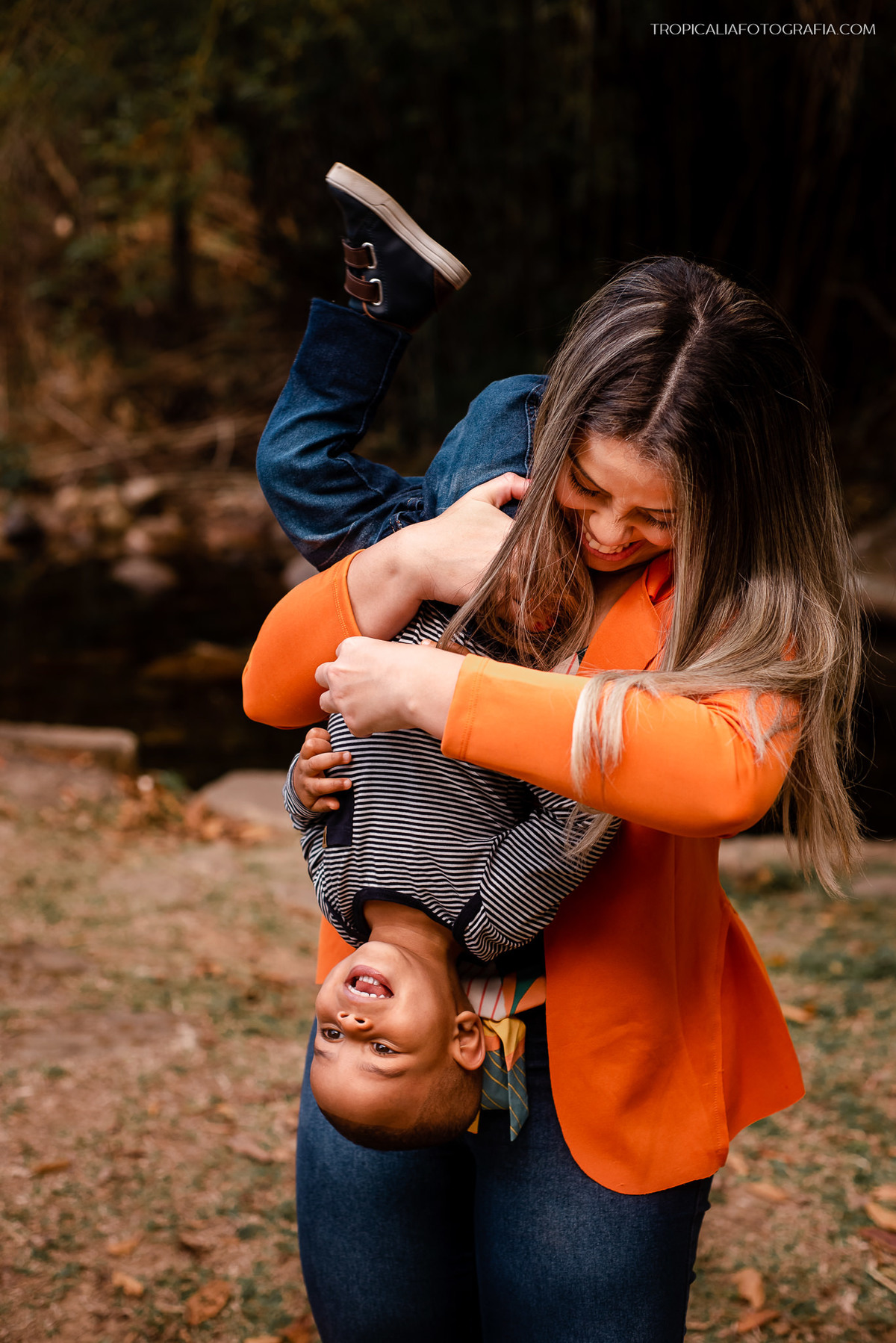 Ensaio documental de família em Nova Friburgo. Foto da mãe brincando com o filho, segurando ele de ponta cabeça