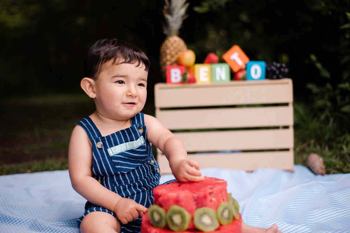 Fotógrafo de família em Nova Friburgo. Ensaio smash the cake da criança. Foto da criança brincando com o bolo de melancia