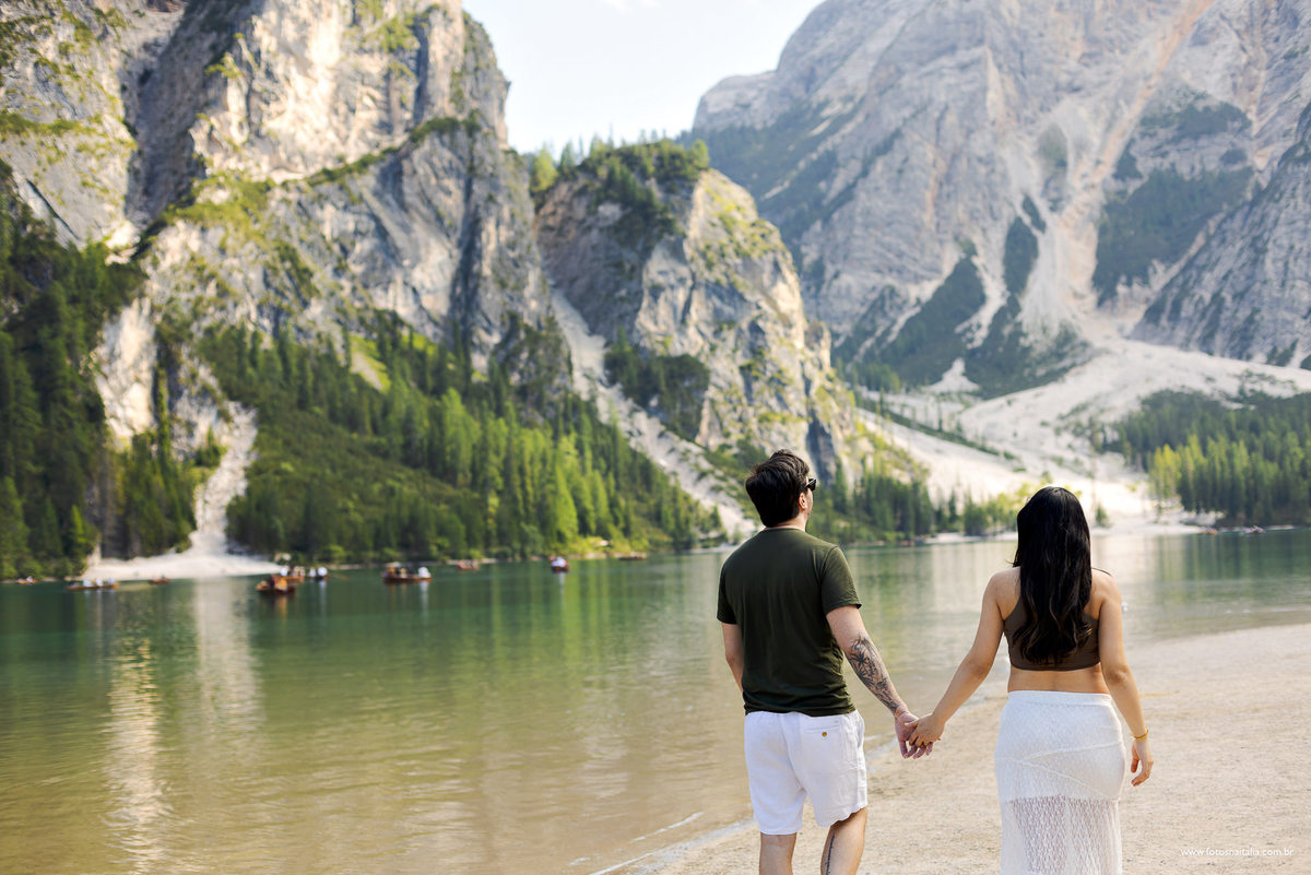 casal caminhando de costas com fundo do lago di braies nas dolomitas