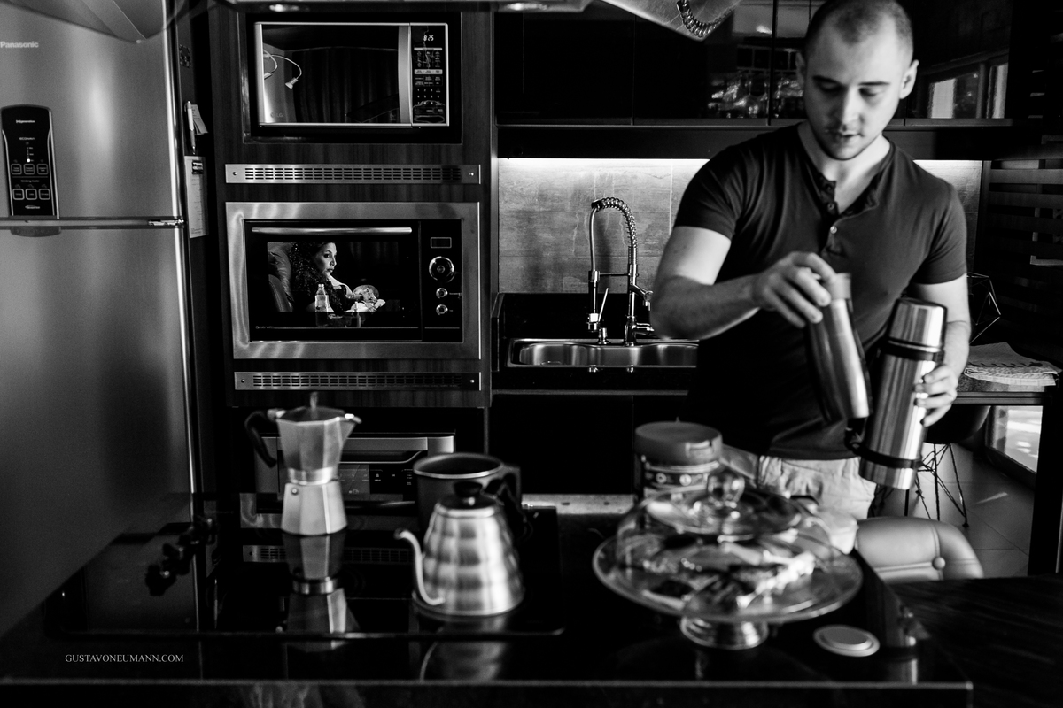 Papai preparando o mamadeira do bebê e mamã refletindo.