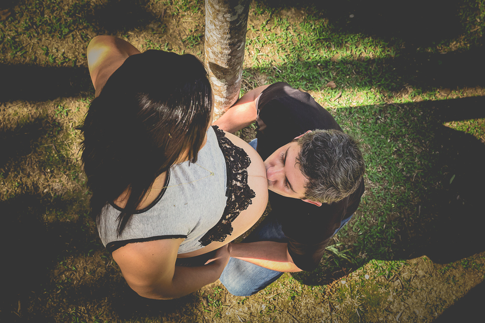 Um beijo do pai na barriga da mãe gestante, gesto de carinho entre o casal. 