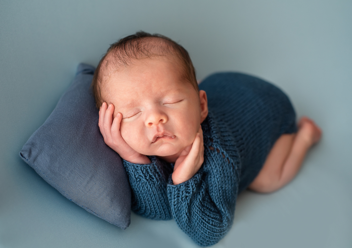 foto de bebê com mãos no queixo