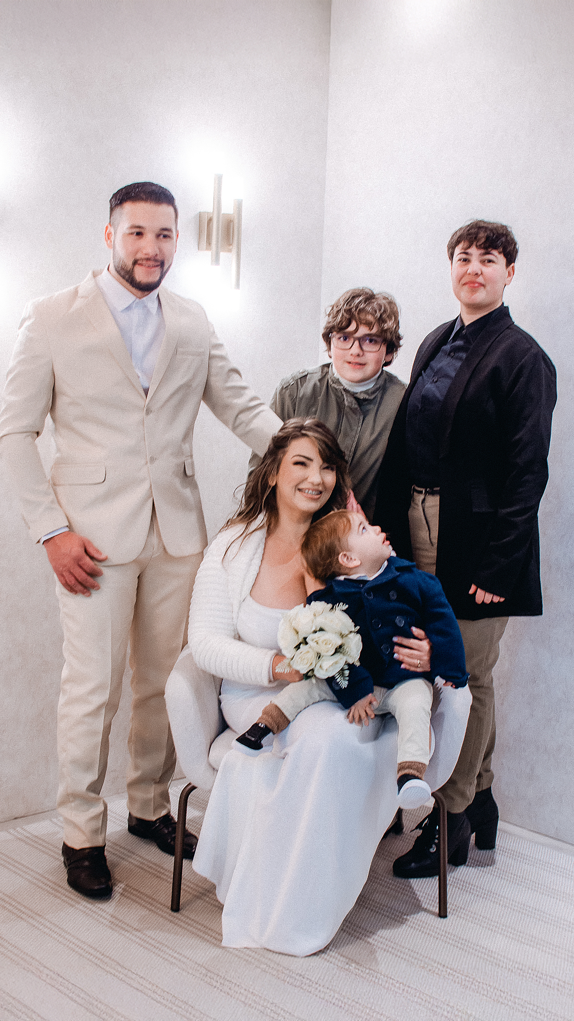 Noiva sorri ao lado de uma criança e familiares durante a sessão de fotografias após o casamento civil.